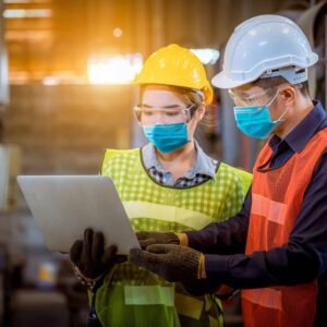 Donna lavoratrice e ingegnere durante ispezione e controllo del processo di produzione che indossano elemtto di sicurezza e maschera di sicurezza per proteggersi da inquinamento in fabbrica